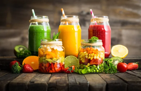 close up view of healthy fresh drinks in glass jars on wooden background