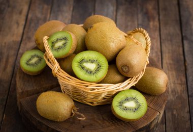 ahşap zemin üzerinde sepet içinde taze kivi görünümü kadar kapatın