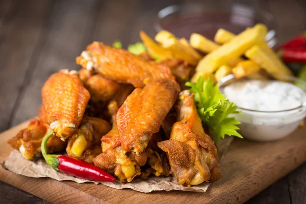 french fries, fried chicken and sauces on wooden tabletop