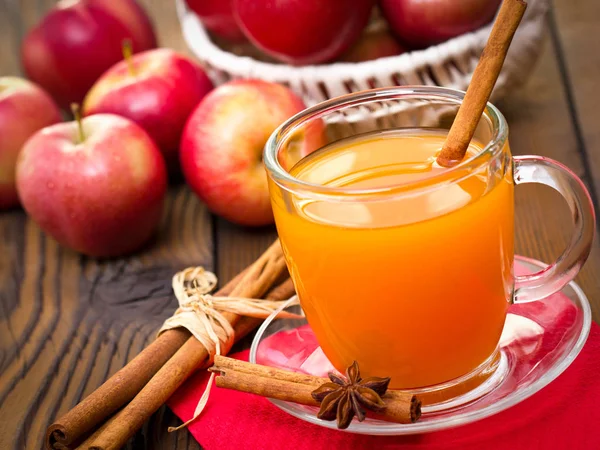 close up view of fresh apple juice and cinnamon on wooden tabletop