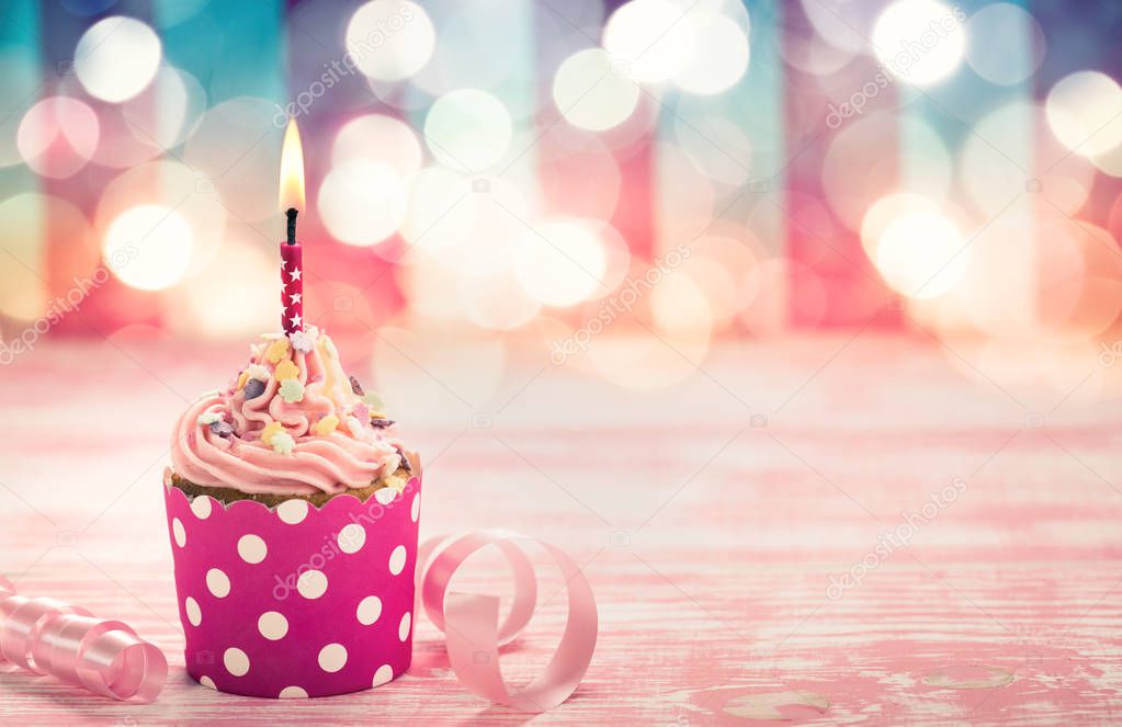 close up view of sweet cupcake with candle on pink wooden table
