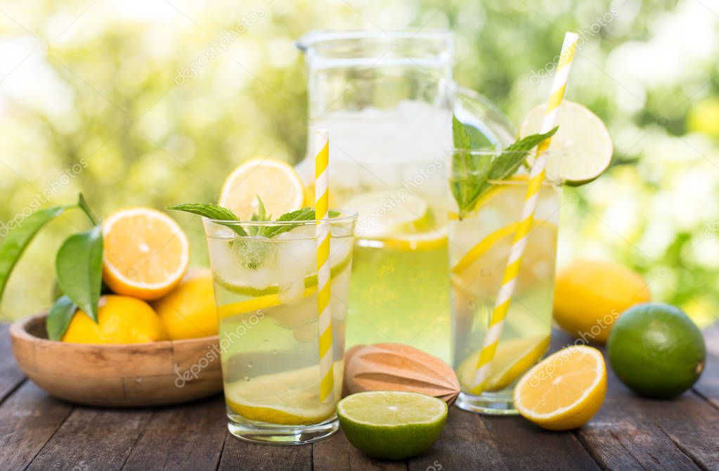 close up view of refreshing citrus drinks with lemons and limes on wooden background