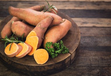 ahşap arka plan üzerinde düzenlenmiş çiğ tatlı patates yakın görünümü