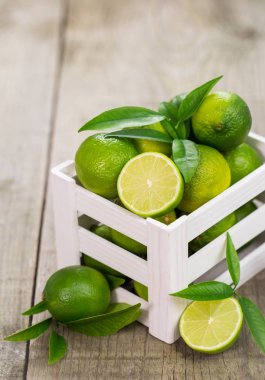 ahşap masa üzerinde beyaz kutu içinde taze Limes görünümü kadar kapatın
