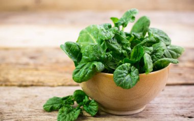 ahşap masa üzerinde kase taze ıspanak görünümü kadar kapatın