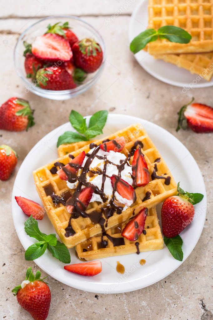 sweet waffles with chocolate and strawberries on wooden backdrop