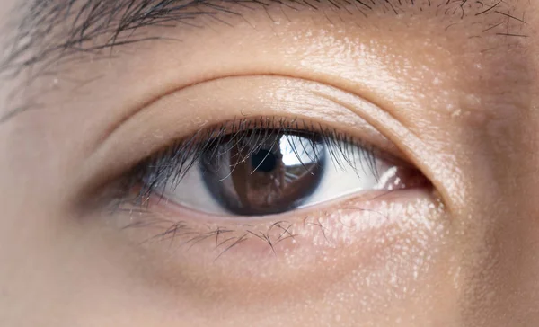 Close-Ups of Asian male\'s eye. Texture of the dark brown eye is visible. Macro detail