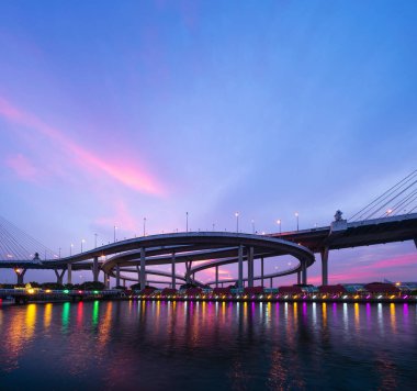 Süspansiyon mimari konsepti, kentsel şehir Bangkok yapısındaki Bhumibol Köprüsü ve Chao Phraya Nehri'nin yansımasıdır. Kent merkezinde gün batımında, Tayland.