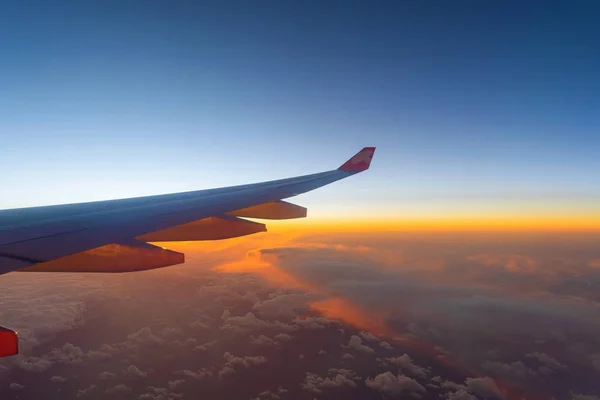Πτέρυγα ενός αεροπλάνου που πετούν πάνω από τα σύννεφα το πρωί με ουρανό — Φωτογραφία Αρχείου
