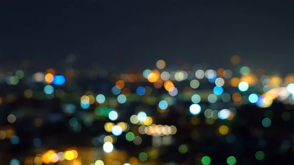 Bokeh of skyscraper buildings in city with lights, Blurry photo at night time. Cityscape background