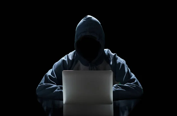 Hacker typing on a laptop isolated on black background with a computer  monitor background matrix, Digital data code in security technology concept. Anonymous