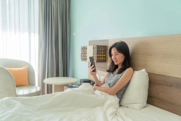 Mulher asiática feliz sorrindo, usando um telefone celular, conversando com f — Fotografia de Stock