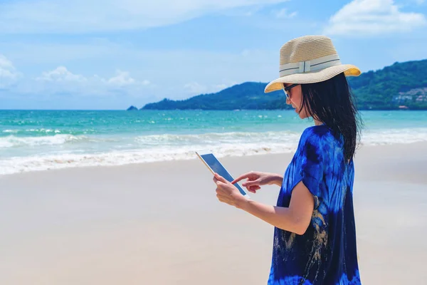 Seyahat holi sırasında plajda bir tablet kullanarak Mutlu Asyalı kadın — Stok fotoğraf