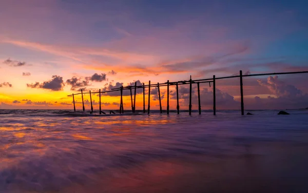 夕焼けの空のビーチの古い木製の橋と海の波 — ストック写真
