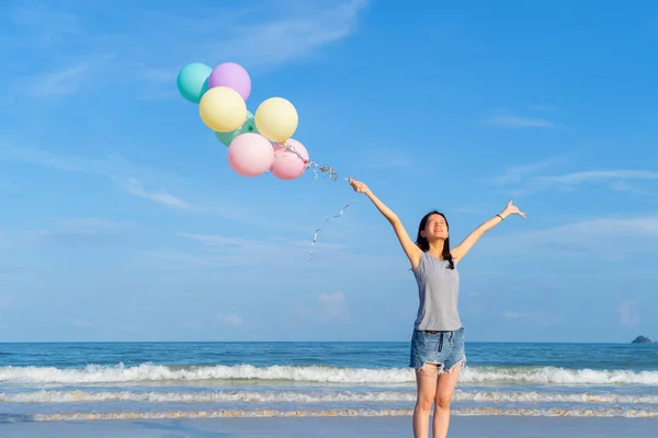 Mutlu Asyalı kadın sırasında plajda renkli balonlar tutan — Stok fotoğraf