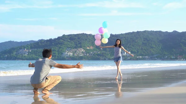 快乐的亚洲夫妇在沙滩上拿着五颜六色的气球 — 图库照片
