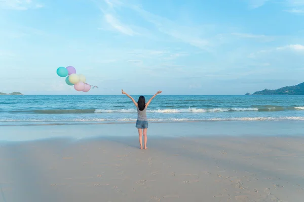 Ευτυχισμένος Ασιάτης/ισσα γυναίκα κρατώντας πολύχρωμα μπαλόνια στην παραλία κατά τη διάρκεια — Φωτογραφία Αρχείου