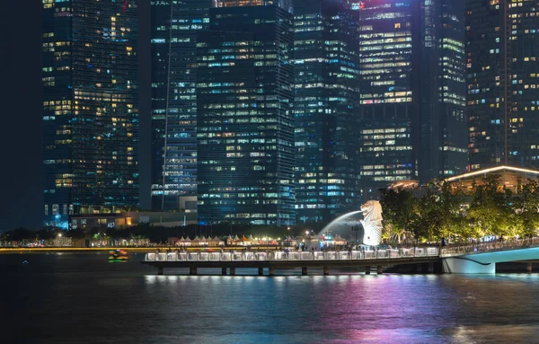 Merlion com edifícios arranha-céus na cidade de Singapura à noite. Fios — Fotografia de Stock