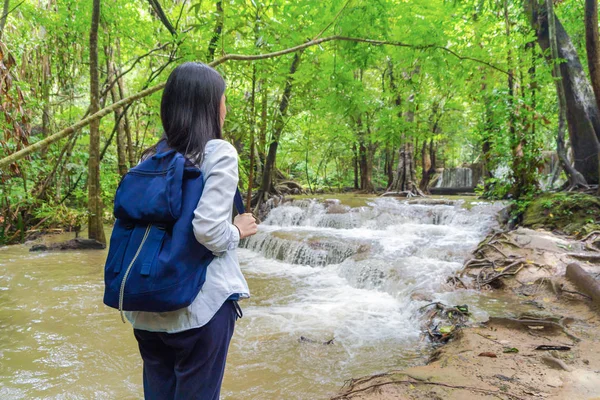 Boldog ázsiai nő, egy hátizsákos, pihentető és élvezi a waterf — Stock Fotó