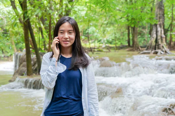 Šťastná asijská žena, která používá mobilní telefon pro rozhovor nebo volání přítele — Stock fotografie