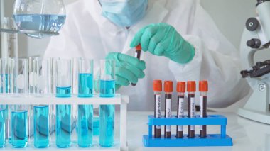 Laboratuvarda veya laboratuarda laboratuvar, tıbbi, kimya, sağlık, araştırma konsepti alanlarında kovid-19 virüsü aşısı geliştirmek ve analiz etmek için kan testi tüpü üzerinde çalışan Asyalı bilim adamı. Deneysel bilim