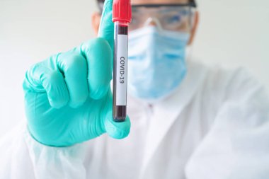 Laboratuvarda veya laboratuarda laboratuvar, tıbbi, kimya, sağlık, araştırma konsepti alanlarında kovid-19 virüsü aşısı geliştirmek ve analiz etmek için kan testi tüpü üzerinde çalışan Asyalı bilim adamı. Deneysel bilim