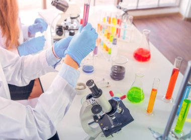 Laboratuvarda ya da laboratuarda teknoloji, kimya, sağlık, araştırma konsepti laboratuvarında covid-19 virüsünün aşısını analiz etmek ve geliştirmek için renkli test tüpleri üzerinde çalışan bilim adamları. Deneysel bilim testi