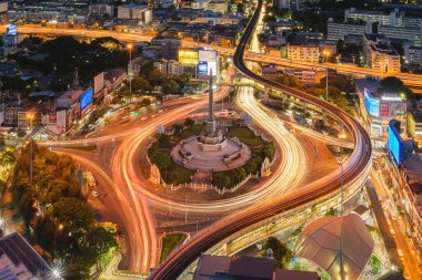 Meşgul sokak yollarında trafik ışığı olan Zafer Anıtı 'nın havadan görünüşü. Bangkok şehir merkezindeki Skyline kavşağında. Tayland. Akıllı şehir merkezindeki finans merkezi. Geceleri gökdelenler.