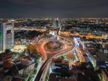 Meşgul sokak yollarında trafik ışığı olan Zafer Anıtı 'nın havadan görünüşü. Bangkok şehir merkezindeki Skyline kavşağında. Tayland. Akıllı şehir merkezindeki finans merkezi. Geceleri gökdelenler.