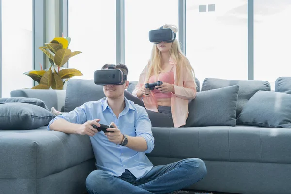 一对身穿Vr或虚拟现实眼镜 头戴耳机 坐在沙发上 在电视前玩电子游戏的西方年轻夫妇在家里的科技创新理念 玩得开心点娱乐 — 图库照片