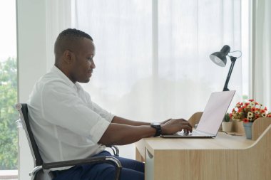 Gülümseyen iş adamı, siyahi Amerikalı, evde bilgisayarlı dizüstü bilgisayarla çalışan Afrikalı insan Corona virüsü pandemik konseptinde karantinada video konferansı düzenliyor..