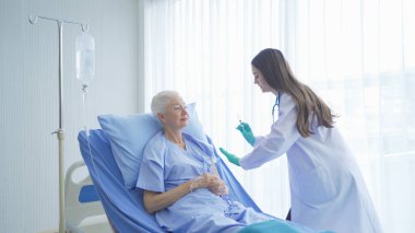 Hasta yaşlı kadın yaşlılara iğne aşı yapan mutlu kadın doktor hastane koğuşunda yatan yaşlı hastaya tıbbi ve sağIık tedavisi konsepti uyguluyor. Kafkasyalı beyazlar.