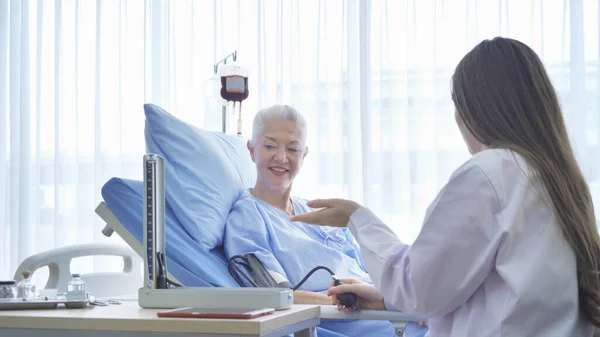 Szczęśliwa Kobieta Lekarz Sprawdzający Badanie Ciśnienia Krwi Chorej Starszej Kobiety — Zdjęcie stockowe