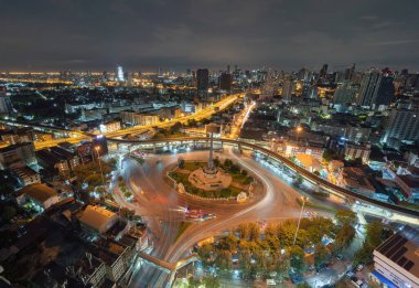Meşgul sokak yollarında trafik ışığı olan Zafer Anıtı 'nın havadan görünüşü. Bangkok şehir merkezindeki Skyline kavşağında. Tayland. Akıllı şehir merkezindeki finans merkezi. Geceleri gökdelenler.