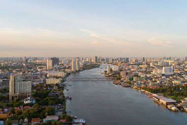Bangkok 'taki Chao Phraya Nehri' nin üzerindeki bir köprünün havadan görüntüsü. Tayland. Finans bölgesi ve akıllı kentlerdeki iş merkezleri. Gün batımında gökdelen ve yüksek binalar.