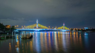 Maha Chesadabodindranusorn Köprüsü veya Nonthaburi Köprüsü Chao Phraya Nehri ve Bangkok silueti, Tayland. Geceleri gökdelen binaları olan şehir ve şehir merkezi. Yansıma.