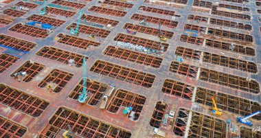 İnşaat işçileri altında vinç ve kazıcılarla çalışan yoğun endüstriyel hava manzarası. Çelik kaplı döşeme öncesi beton döşeme manzarası. Yüksek binalı mimari bina geliştirme.