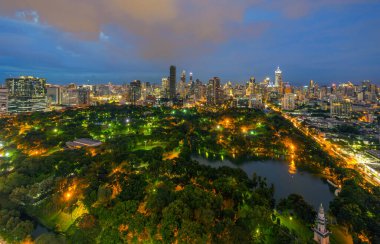 Lumpini Park 'taki yeşil ağaçların havadan görünüşü, Sathorn bölgesi, Bangkok şehir merkezi Skyline. Tayland. Asya 'nın akıllı kentindeki finans bölgesi ve iş merkezi. Geceleri gökdelen binaları.