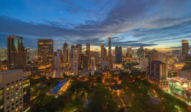 Lumpini Park 'taki yeşil ağaçların havadan görünüşü, Sathorn bölgesi, Bangkok şehir merkezi Skyline. Tayland. Asya 'nın akıllı kentindeki finans bölgesi ve iş merkezi. Geceleri gökdelen binaları.