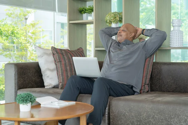 Smiling business senior old elderly Black American man, African person working from home on table with computer notebook laptop in quarantine in corona virus pandemic concept.