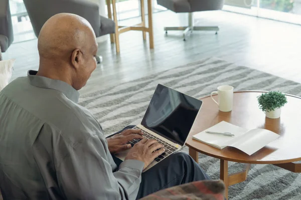ビジネスシニア高齢者黒人アメリカ人男性 アフリカ人は コンピュータノートパソコンやコロナウイルスの隔離でウェブカメラのビデオ通話会議で空白の画面とテーブルの上に自宅から働いています — ストック写真