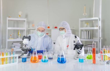 Batılı bir bilim adamı çifti laboratuvar, tıbbi, kimya, sağlık ve araştırma laboratuarlarında kovid-19 virüsü aşısı geliştirmek ve analiz etmek için test tüpü üzerinde çalışıyor. Deneysel bilim.