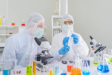 Batılı bir bilim adamı çifti laboratuvar, tıbbi, kimya, sağlık ve araştırma laboratuarlarında kovid-19 virüsü aşısı geliştirmek ve analiz etmek için test tüpü üzerinde çalışıyor. Deneysel bilim.