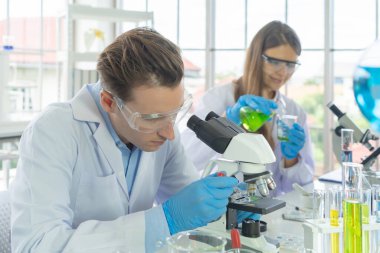 Batılı bir bilim adamı çifti laboratuvar, tıbbi, kimya, sağlık ve araştırma laboratuarlarında kovid-19 virüsü aşısı geliştirmek ve analiz etmek için test tüpü üzerinde çalışıyor. Deneysel bilim.