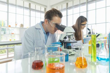 Batılı bir bilim adamı çifti laboratuvar, tıbbi, kimya, sağlık ve araştırma laboratuarlarında kovid-19 virüsü aşısı geliştirmek ve analiz etmek için test tüpü üzerinde çalışıyor. Deneysel bilim.