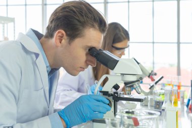 Batılı bir bilim adamı çifti laboratuvar, tıbbi, kimya, sağlık ve araştırma laboratuarlarında kovid-19 virüsü aşısı geliştirmek ve analiz etmek için test tüpü üzerinde çalışıyor. Deneysel bilim.