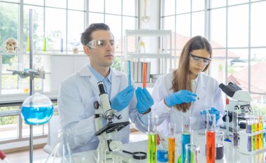 Batılı bir bilim adamı çifti laboratuvar, tıbbi, kimya, sağlık ve araştırma laboratuarlarında kovid-19 virüsü aşısı geliştirmek ve analiz etmek için test tüpü üzerinde çalışıyor. Deneysel bilim.