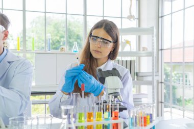 Batılı bir bilim adamı çifti laboratuvar, tıbbi, kimya, sağlık ve araştırma laboratuarlarında kovid-19 virüsü aşısı geliştirmek ve analiz etmek için test tüpü üzerinde çalışıyor. Deneysel bilim.