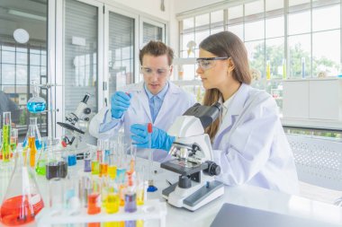 Batılı bir bilim adamı çifti laboratuvar, tıbbi, kimya, sağlık ve araştırma laboratuarlarında kovid-19 virüsü aşısı geliştirmek ve analiz etmek için test tüpü üzerinde çalışıyor. Deneysel bilim.