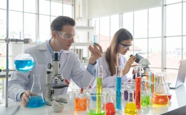 Batılı bir bilim adamı çifti laboratuvar, tıbbi, kimya, sağlık ve araştırma laboratuarlarında kovid-19 virüsü aşısı geliştirmek ve analiz etmek için test tüpü üzerinde çalışıyor. Deneysel bilim.